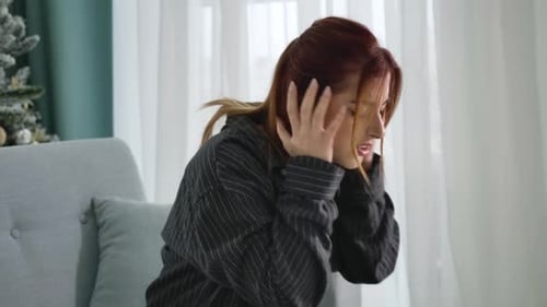 Side View of Young Caucasian Woman Suffering From Headache on Christmas. Beautiful Redhead Lady