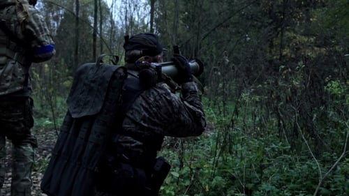 Un militaire dans la forêt tire avec un lance-grenades