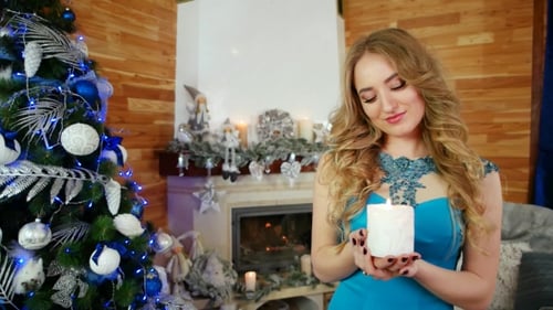 Woman Holding Candle by Christmas Tree and Fireplace