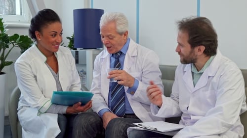 Medical Team of Three Doctors Sits on the Couch at the Hospital