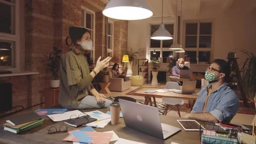 Male and Female Colleagues in Masks Talking at Work in Loft Office