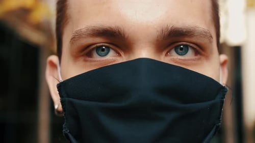 Young Adult Wears Mask, Looking Directly at Camera