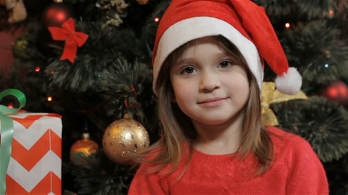 Girl with Santa Hat in Front of Christmas Tree