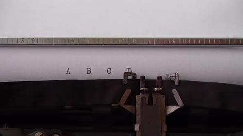 Typing alphabet letters A B C D E on retro typewriter. Close up.