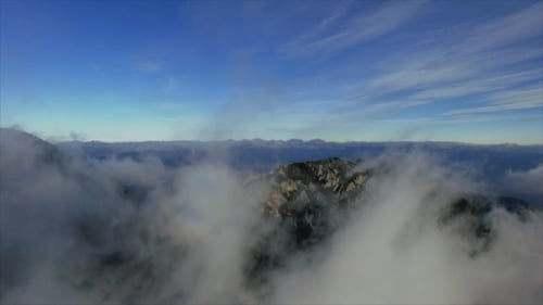 Fliegen durch Wolken über Klippen und Berge