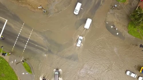 Aerial view of traffic cars driving on flooded road with rain water.