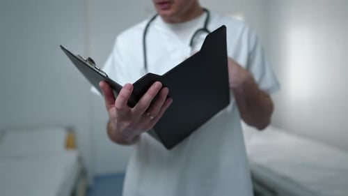 Closeup Medical History in Hands of Concentrated Doctor Analyzing Test Results