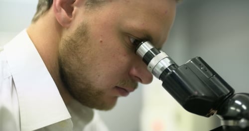 Man Looking into Microscope in Laboratory Close Up