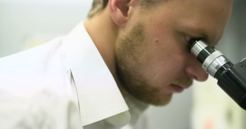 Scientist Examining Specimen Through Microscope in Lab