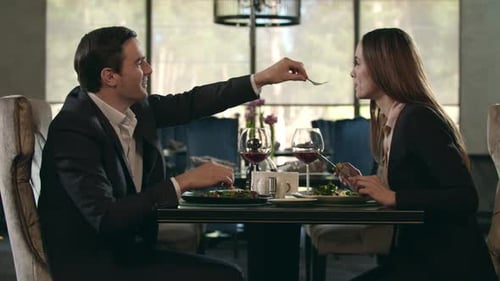 Romantic Couple Eating at Restaurant. Man Give Food To Woman at Romantic Dinner