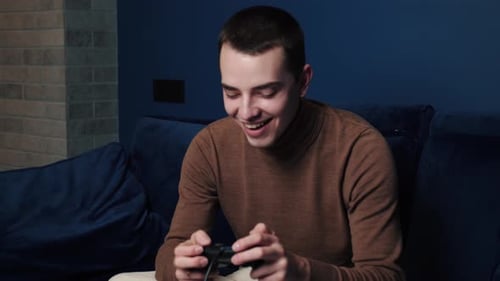 Excited Young Man Plays Video Game at Home