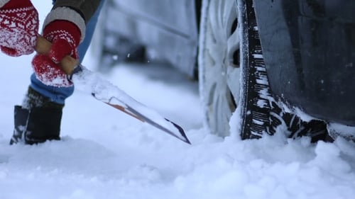 Woman Digging Car out of Snow with Shovel
