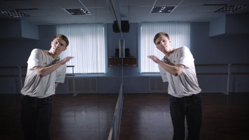 Dancer in White Shirt and Jeans Showing Modern Breakdancing in Classroom with Mirrors and Ballet