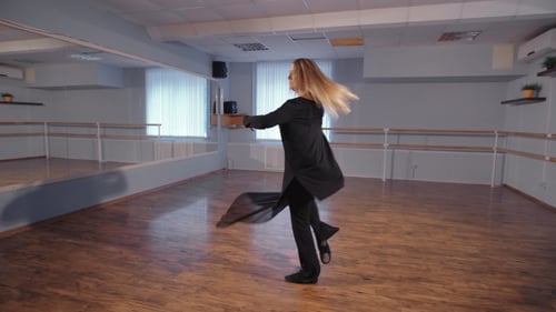 A Woman in an Empty Studio Takes Dance Lessons. This Is Her Hobby. She Rehearses in a Good Mood
