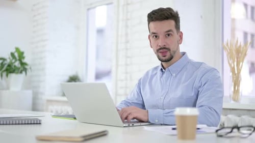 Young Adult Working on Laptop in Bright Office