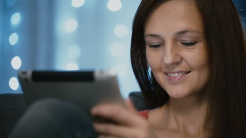 Mujer atractiva usando una tableta en casa en Nochebuena