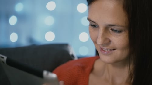 Mujer atractiva usando una tableta en casa en Nochebuena