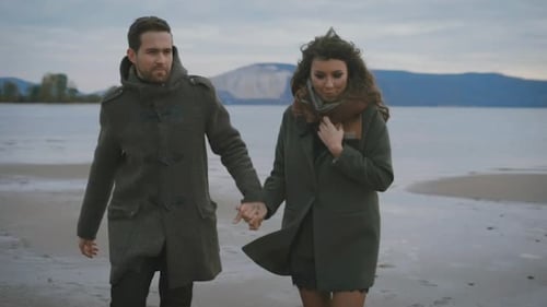 Stylish Couple Walking Hand-in-Hand on Sandy Beach