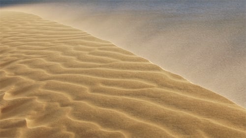 Sand Blowing Over The Dunes in The Desert