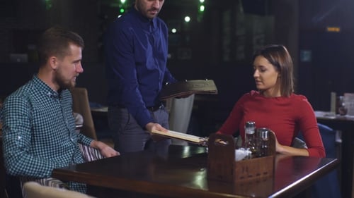 Cheerful Couple with Menu in a Restaurant Making Order