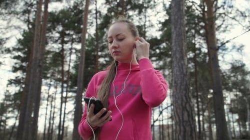 Woman Listens to Music on Phone in Park
