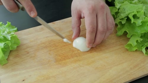 Slicing Onion on Cutting Board with Lettuce