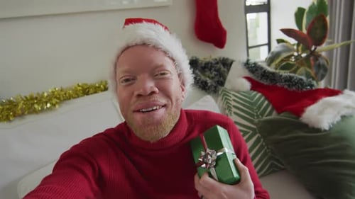 Happy albino african american man wearing santa hat making video call at christmas