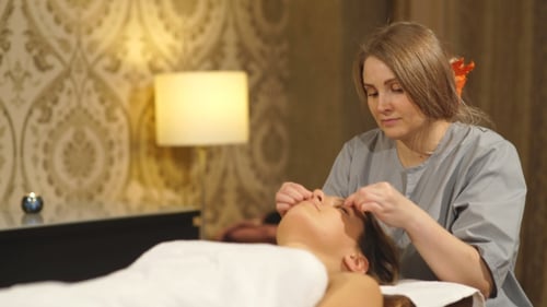 Beautiful Brunette Doing a Facial Massage in a Spa Center