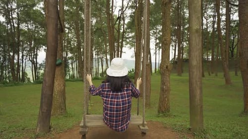 Happy Asian woman swinging on a swing in forest trees