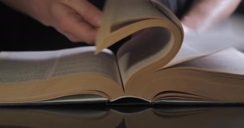 Hand Flips Through Pages of Open Book
