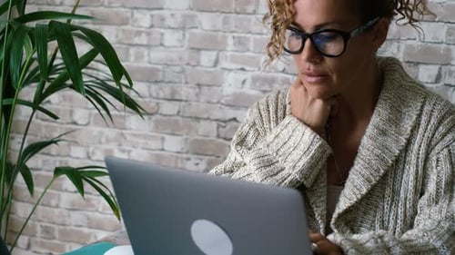 Woman Works Thoughtfully on Laptop From Home