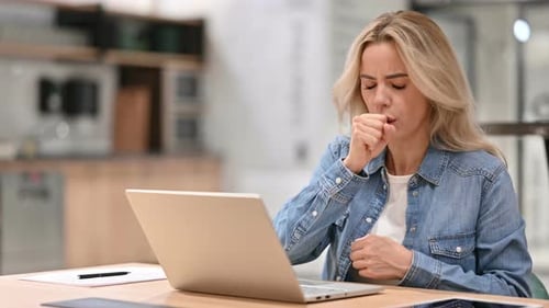 Woman Coughing While Working on Laptop at Home