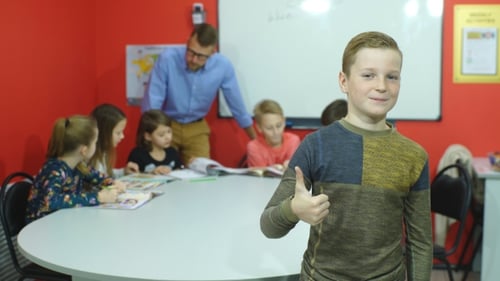 Smiling Boy Gives Thumbs Up in Classroom