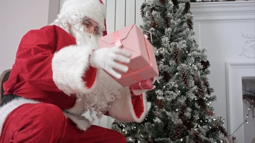 Santa Claus Placing Present into Red Bag