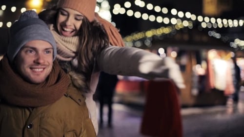 Happy Couple Piggyback Ride at Holiday Market at Night