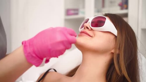 Kosmetikerin macht Laser-Gesichtshaarentfernung Schöne Frau im Schönheitssalon
