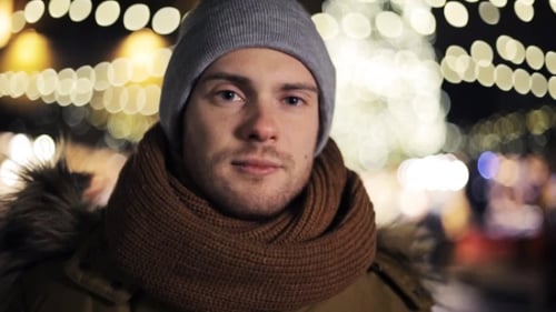 Smiling Young Adult with Christmas Lights Background