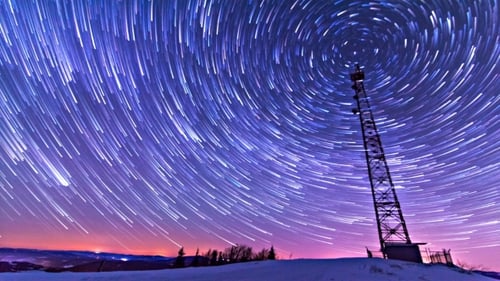 Star Trails Swirl Above Snowy Hill and Tower