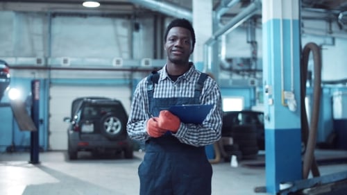 Smiling African Mechanic Writing Out a Job Sheet