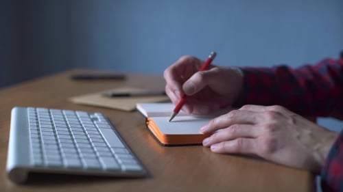 Writing in a Notebook at Desk in Workplace