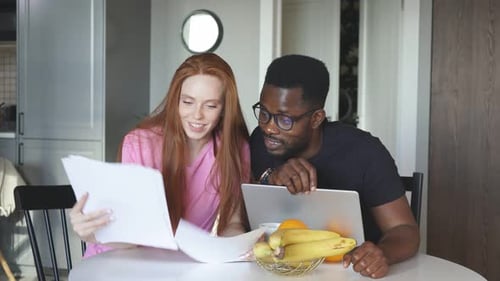 Young Adults Collaborate on Project With Laptop and Documents