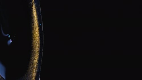 Liquid with Gold Glittery Streak on Black Background