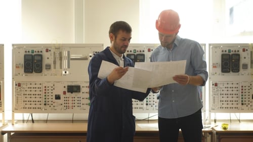 Young Engineer Taking Notes at Control Room in Factory