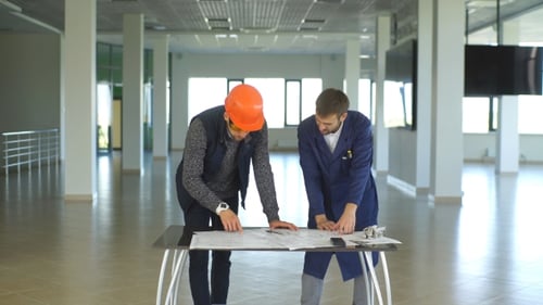 Architecte ou ingénieur travaillant sur un plan et un modèle d'architecture dans le hall