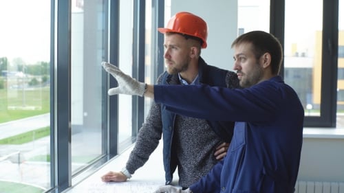 Fröhlicher junger Vorarbeiter zeigt dem Architekten die Probleme des Bauens