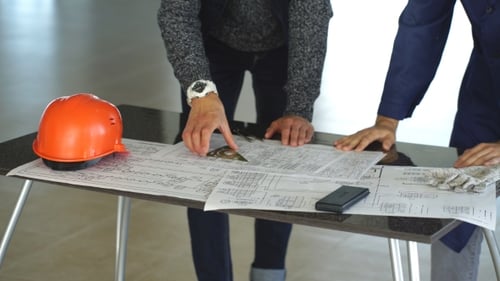 Architect or Engineer Working on Blueprint and Architecture Model in Office Room