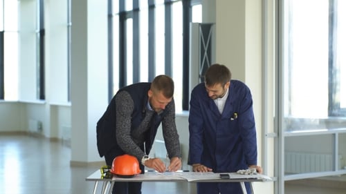 Architekt oder Ingenieur arbeitet in Hall an Bauplan und Architekturmodell