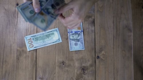 Dollar-Banknoten, die auf einen Holztisch fallen.