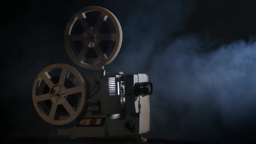 Vintage Film Projector Shining Bright Light in Dark Room