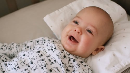 A Cute Little Baby Is Happy Smiling Lying in a Bed